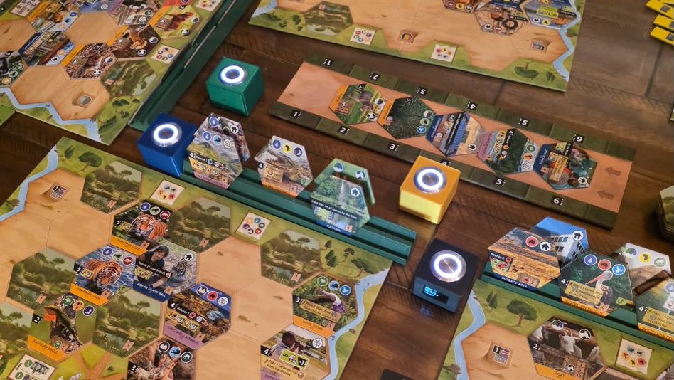 Four OLO buttons glowing across a board game mid-play