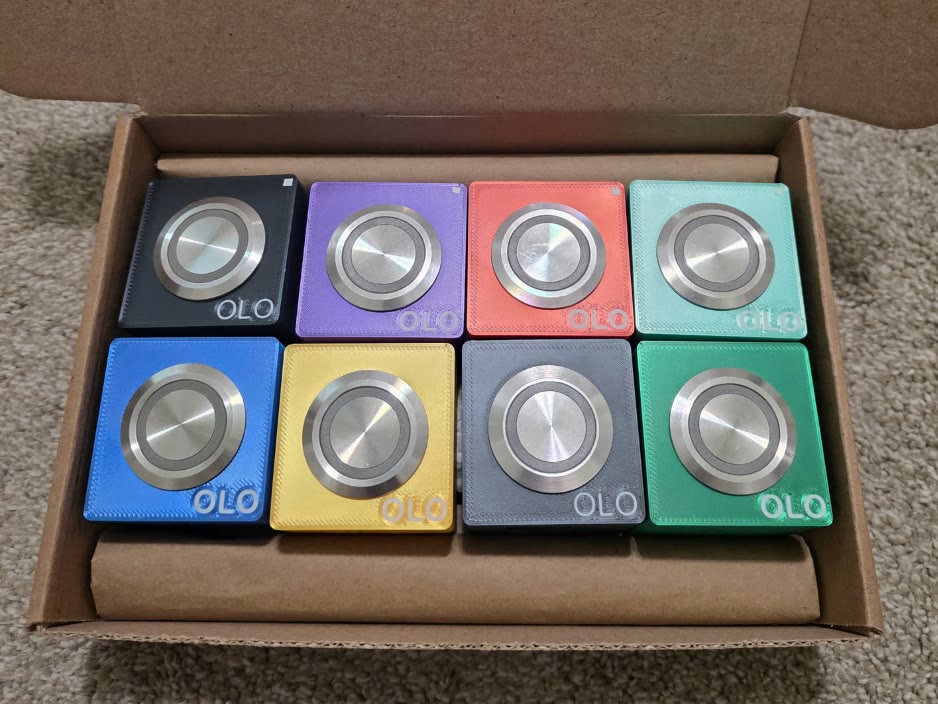 Eight OLO buttons in a box, one of each color